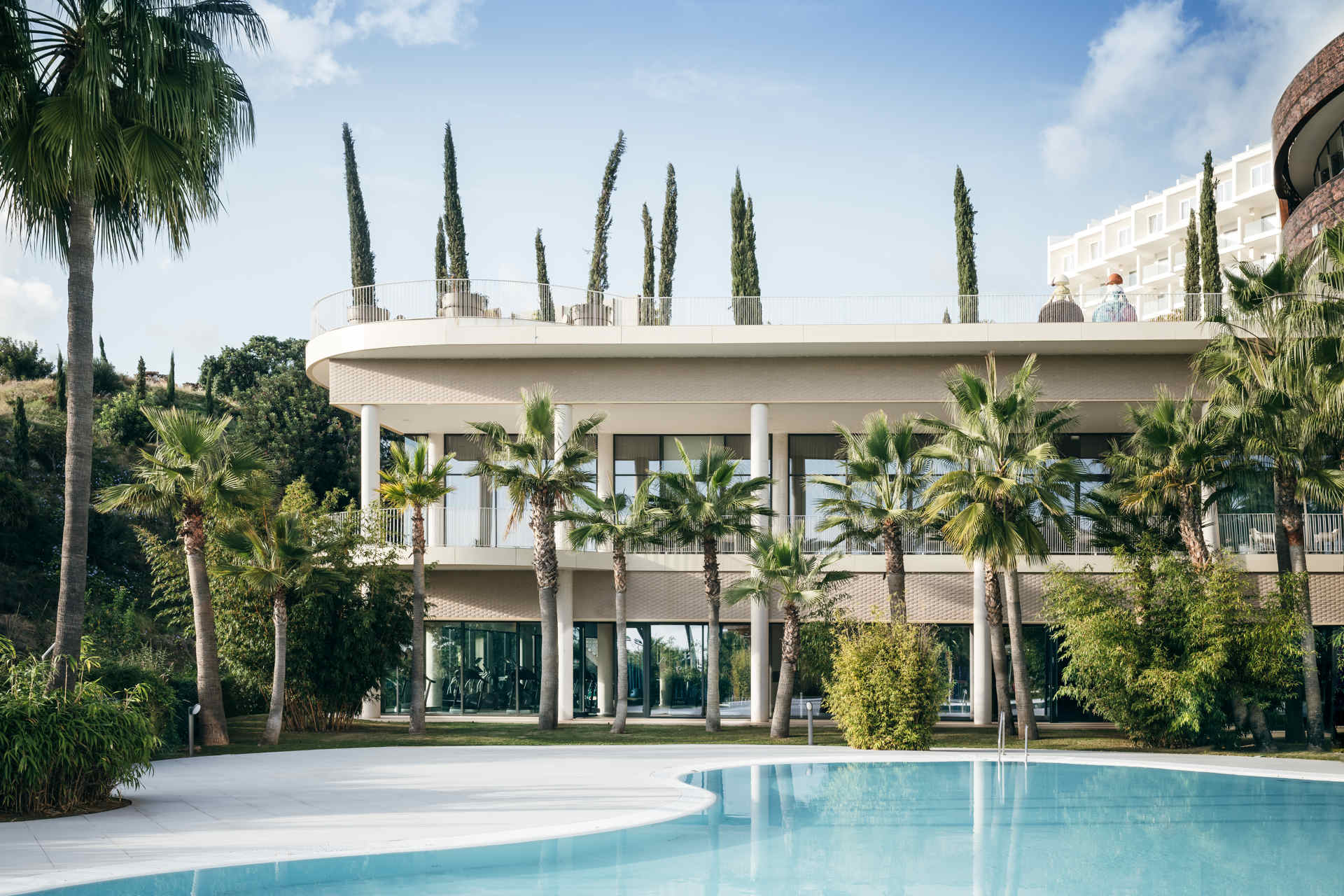 Piscina y fachada de Higuerón Hotel Málaga, rodeadas de palmeras